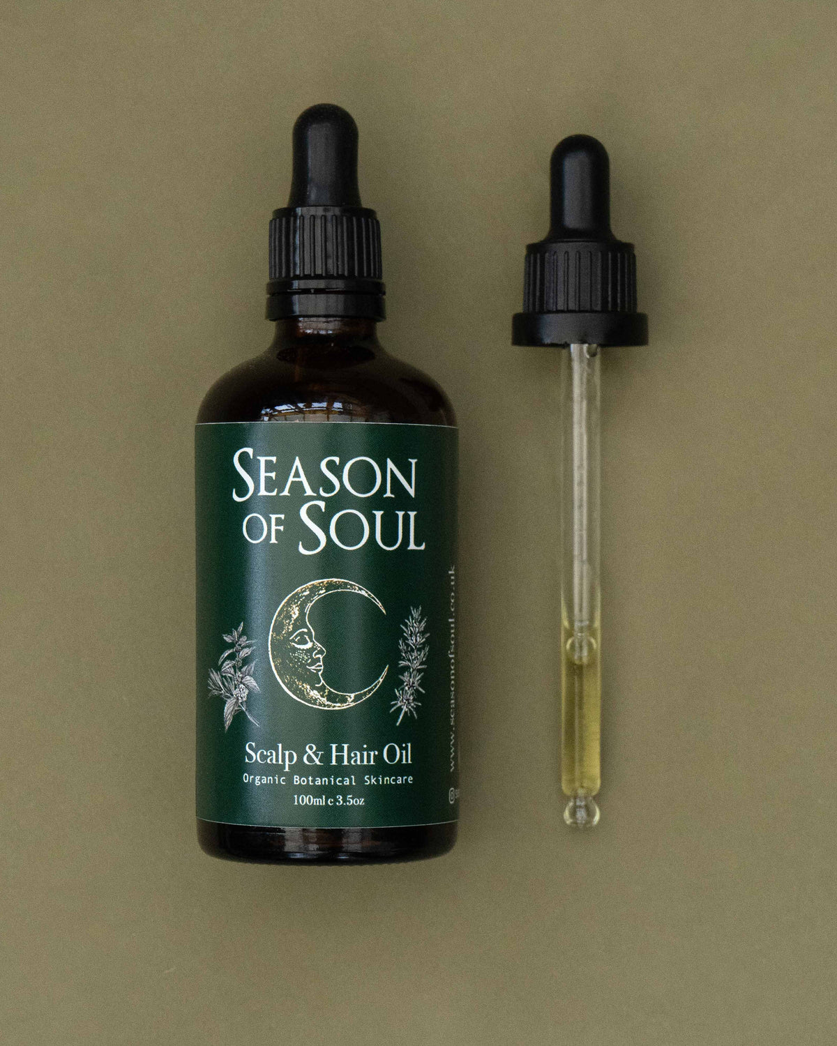 Bottle of 'Season of Soul' scalp and hair oil with a dropper on a green background