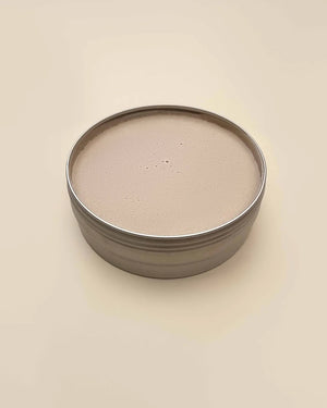 Round metal container with a beige lid on a beige background