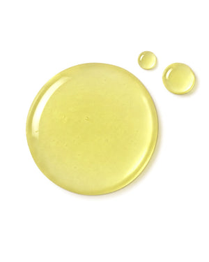A glossy, translucent droplet of pale yellow cosmetic or liquid product on a solid white background, with two smaller droplets to the upper right of the main droplet.