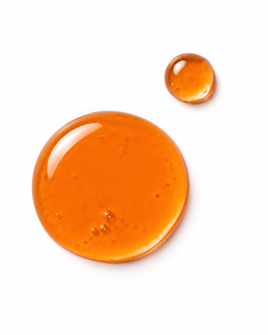Two glossy orange translucent droplets of rosehip oil on a clean white background, one large and one small.