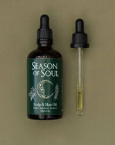 Bottle of 'Season of Soul' scalp and hair oil with a dropper on a green background