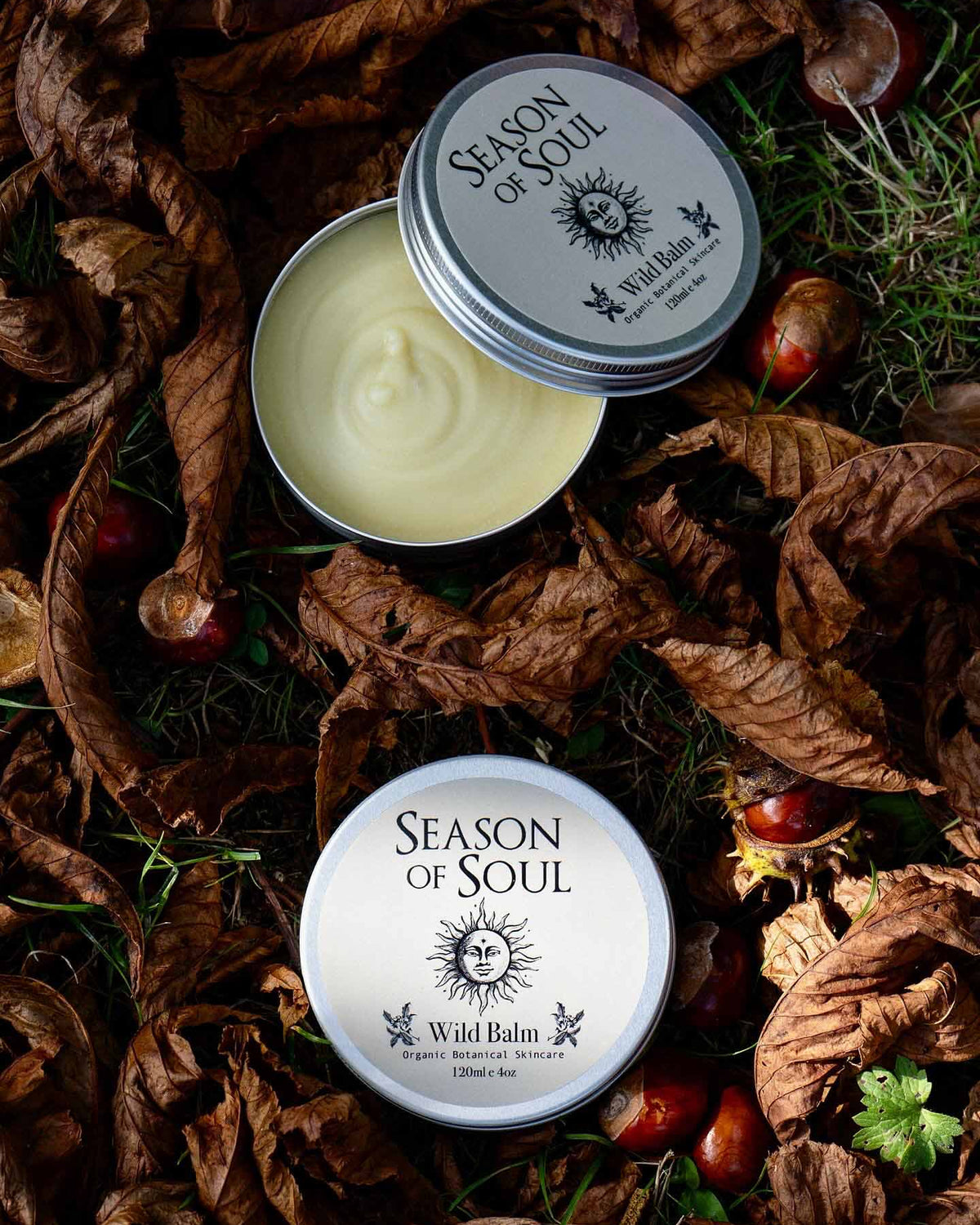 Two tins of 'Season of Soul' Wild Balm on a natural background with leaves and berries.